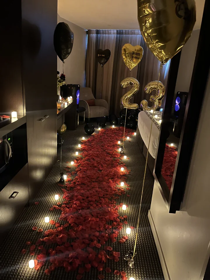 Rose-petal pathway and LED candle styling in a hotel room reveal.