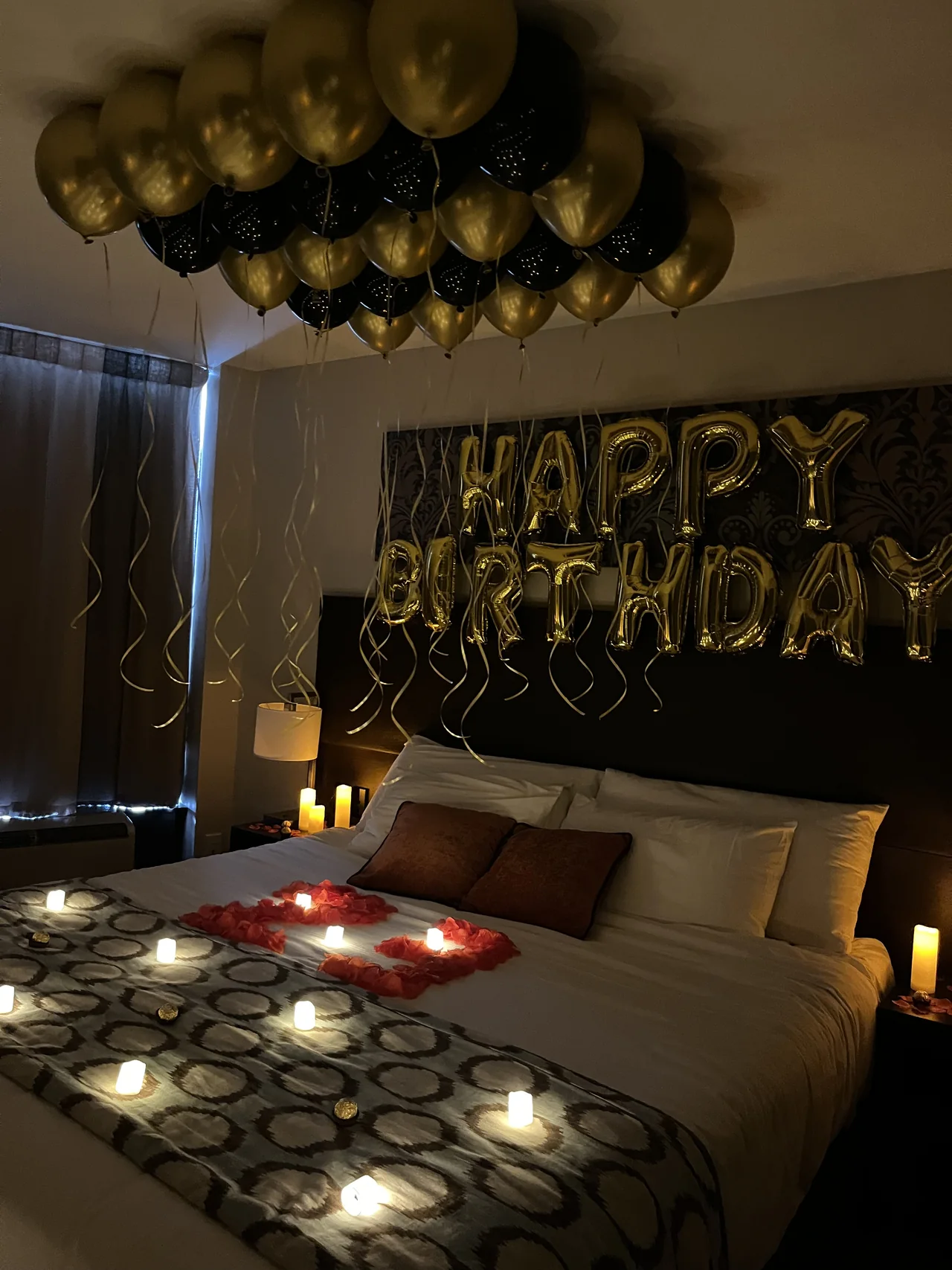 Hotel room reveal with ceiling balloons, rose petals and LED candles.