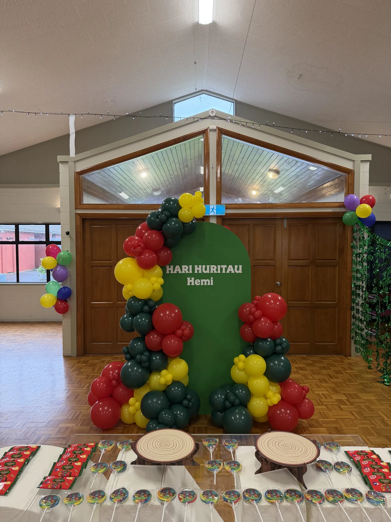 Green personalised backdrop with red, yellow and green balloon styling.